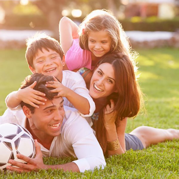 Family Lying In Pile Up On Grass Together